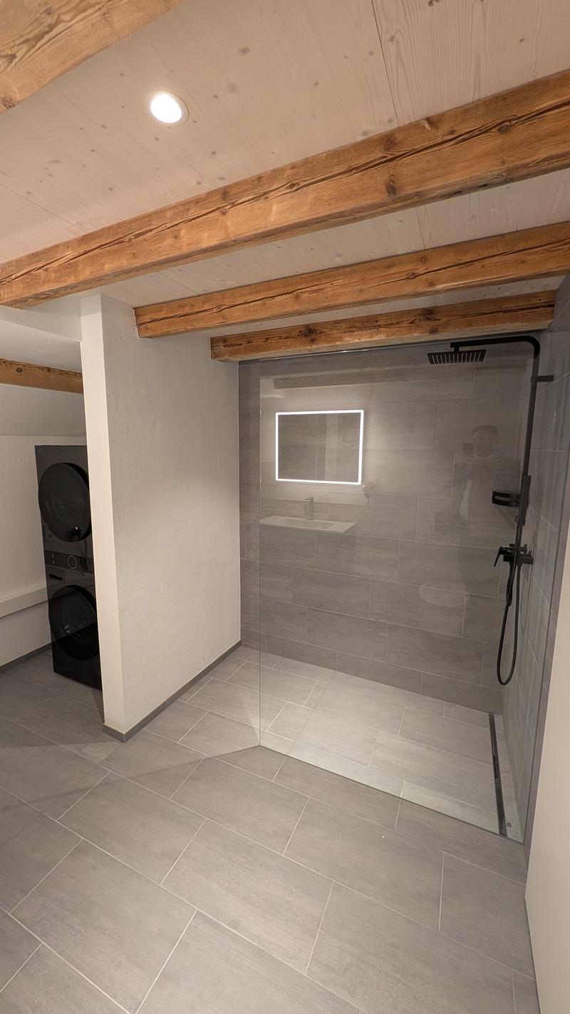 Modern bathroom with a glass shower enclosure, a mirror, and a washing machine.