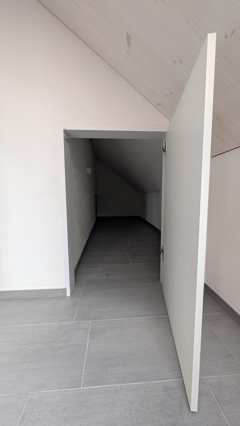 Empty room with white walls, gray floor, open door, wooden ceiling