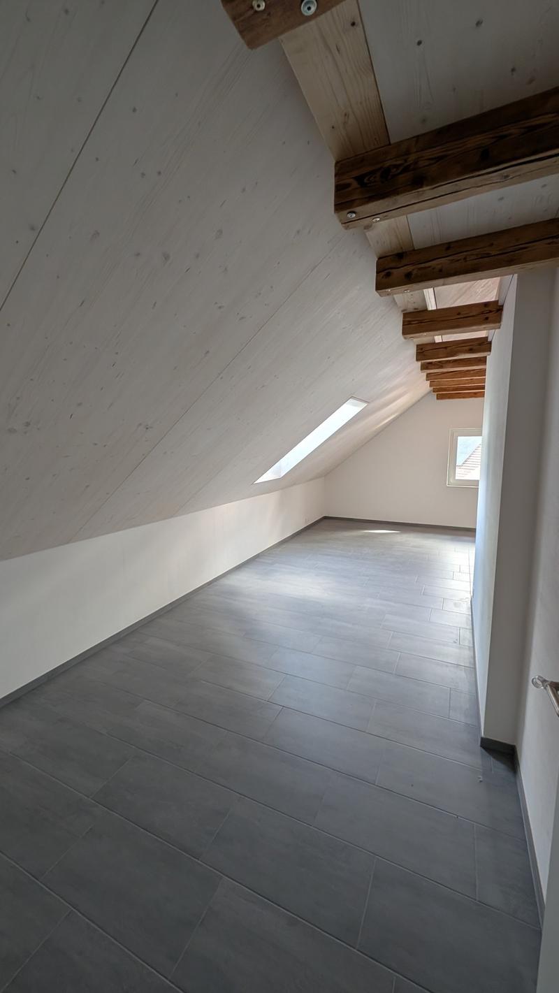 empty attic room, wooden beams, gray tiles, white walls, two windows