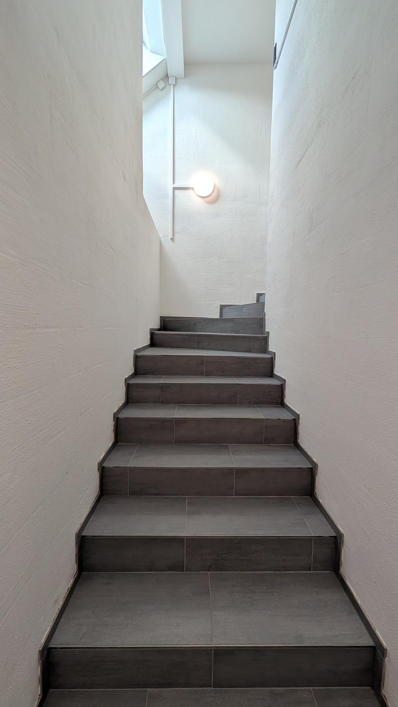Gray tiled staircase, white walls, round ceiling light
