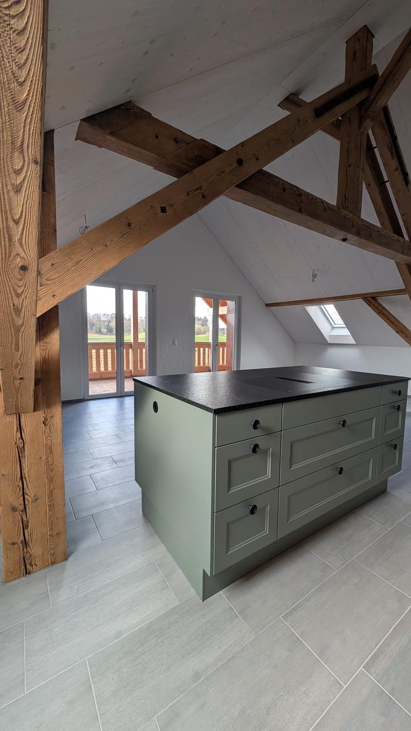 kitchen island with drawers and black countertop, wooden beams, glass doors, tiled floor