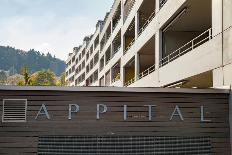 Apartment building with multiple floors, balconies, and a sign reading 'APPITAL'.