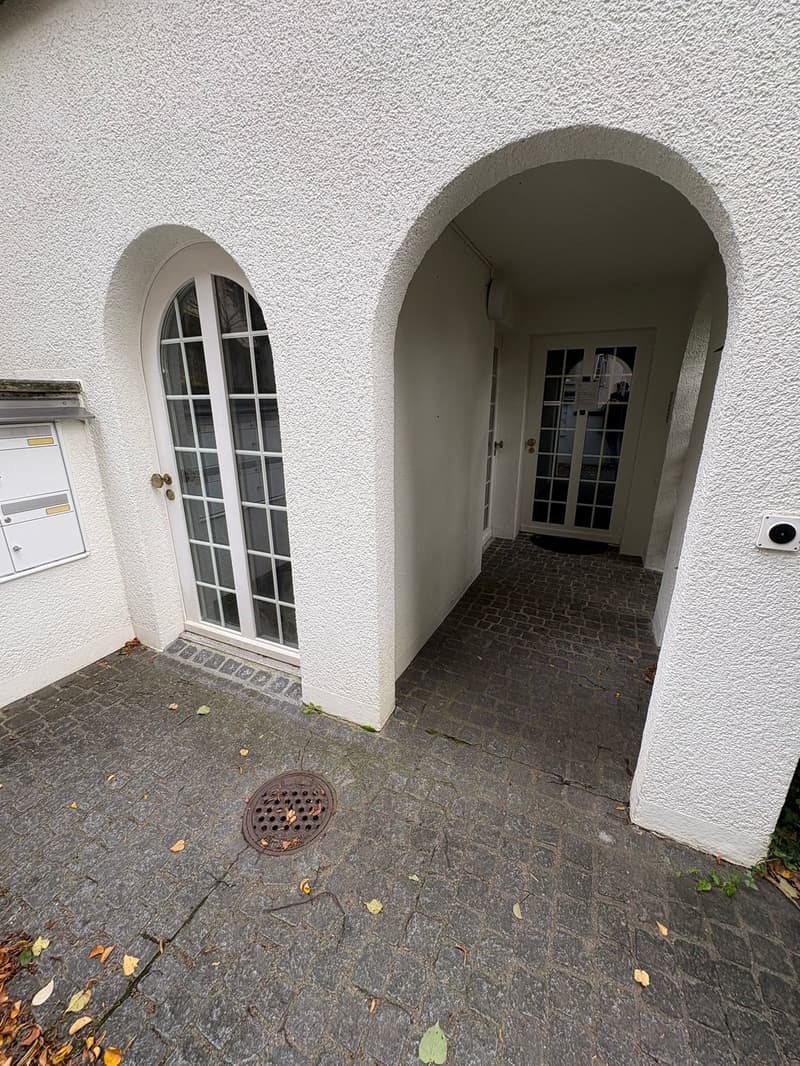 two arched doorways, paved entry, mailbox on left, doormat near entrance
