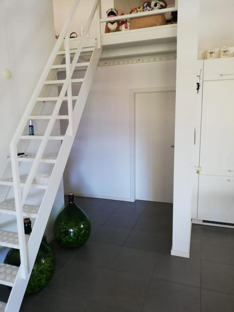 empty room with stairs, a few decorative items, tiled floor, white walls, and large doors