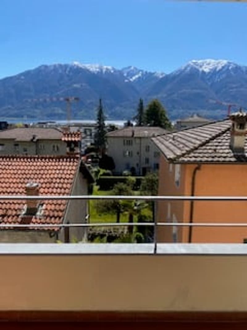 Outdoor balcony with a view of the mountains and buildings.