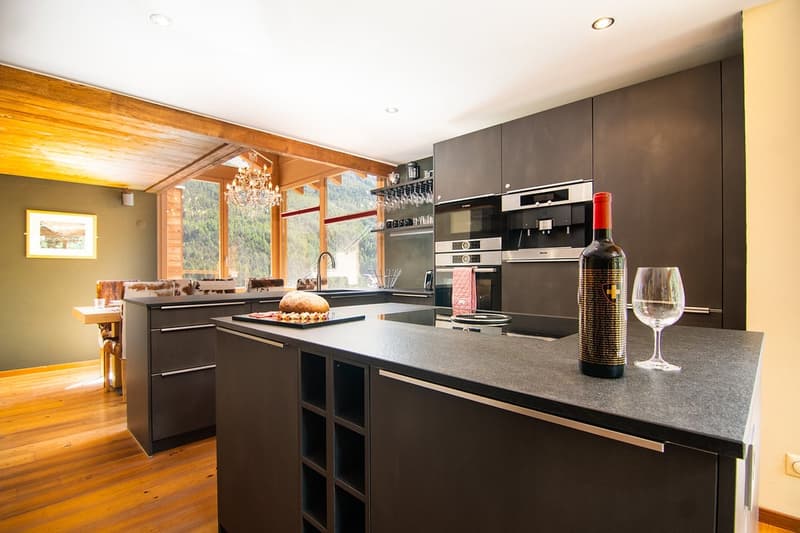 black modern kitchen, wine bottle, wine glass, chandelier, large window, kitchen island, oven, sink