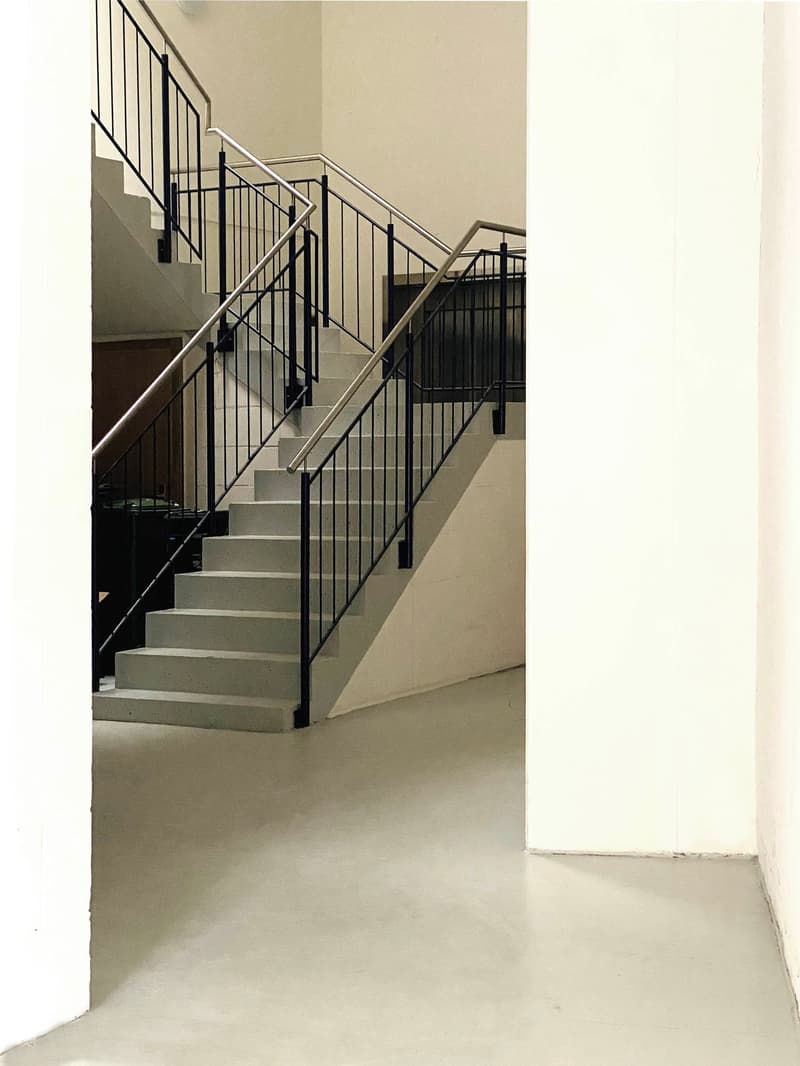 White marble flooring, gray concrete stairs, black railings, bright and spacious area