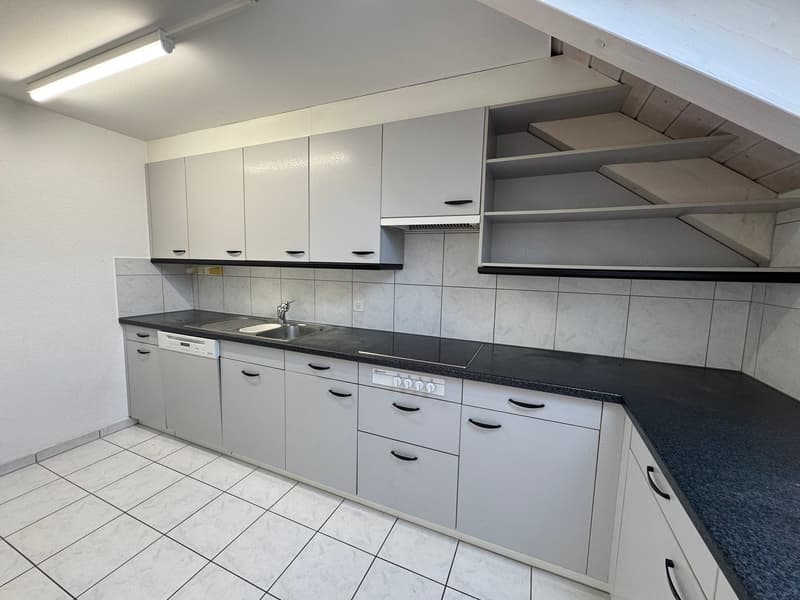 Spacious kitchen with gray cabinets, black countertops, tiled backsplash, and built-in dishwasher