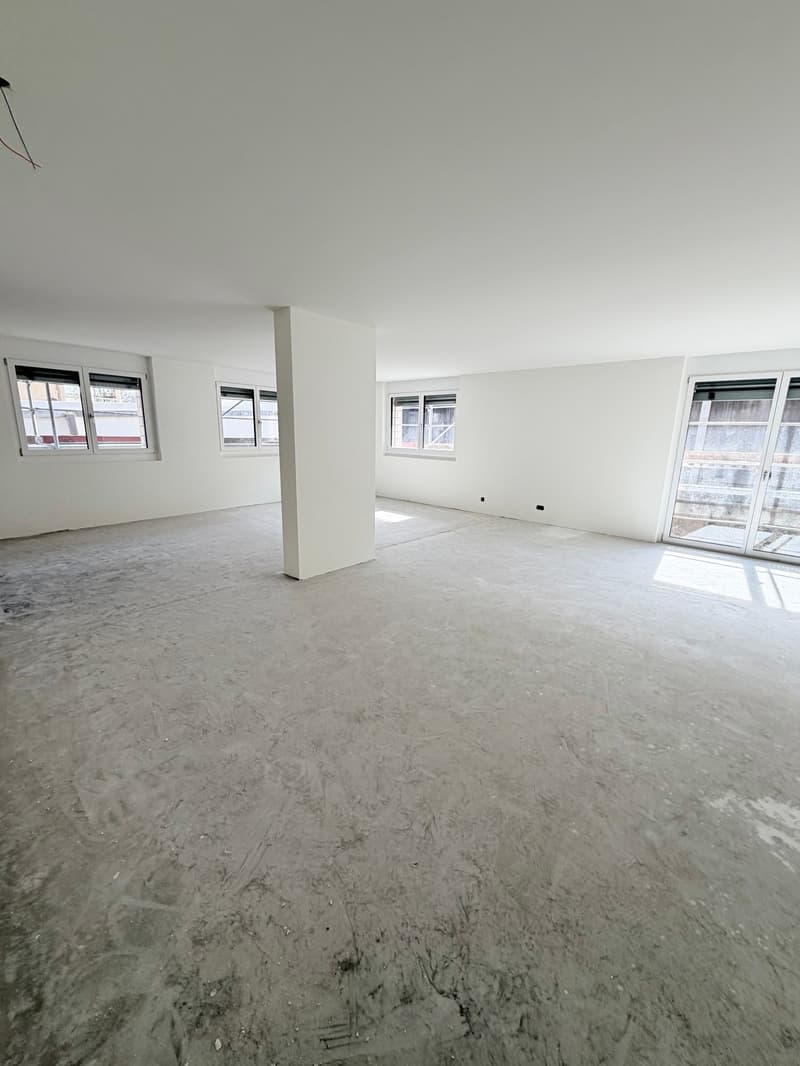 Empty room with white walls, concrete floor, three windows, and a pillar