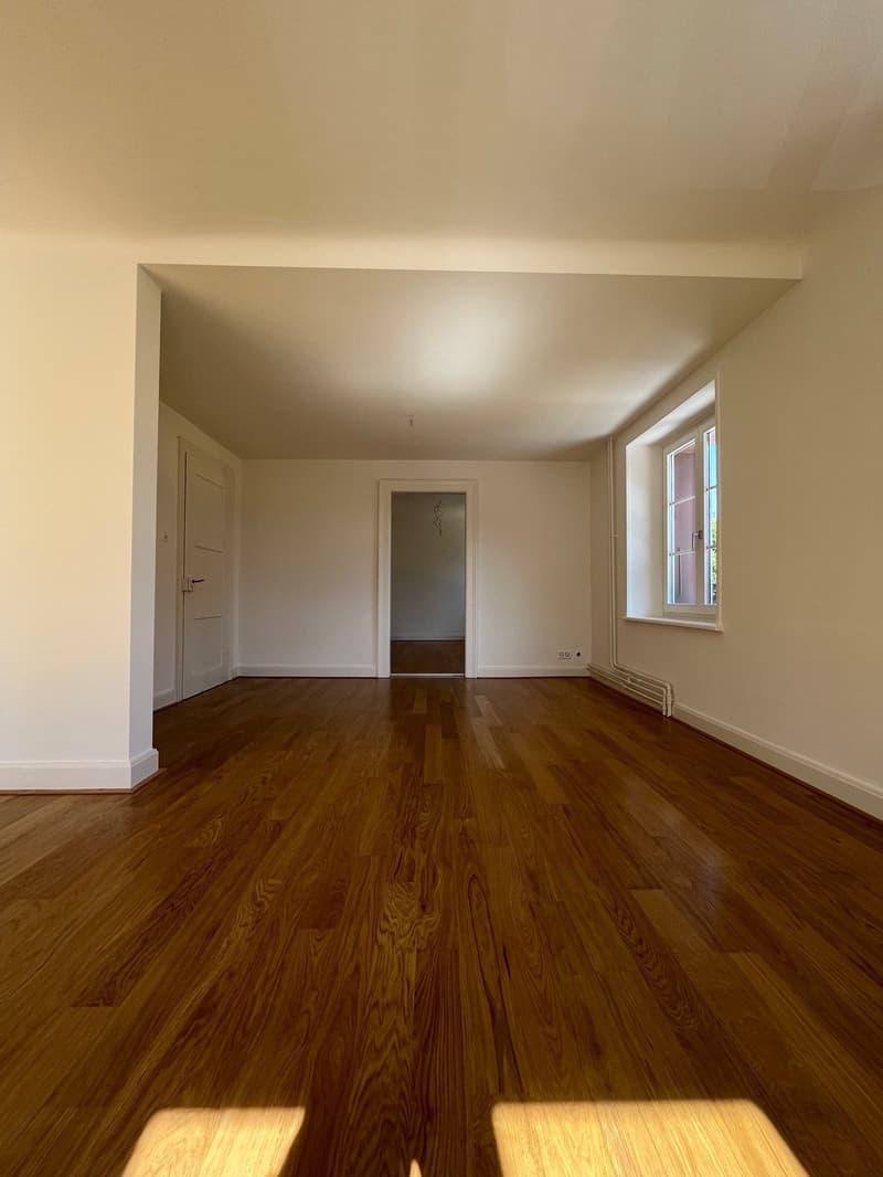 Hardwood floors, white walls, large window, door