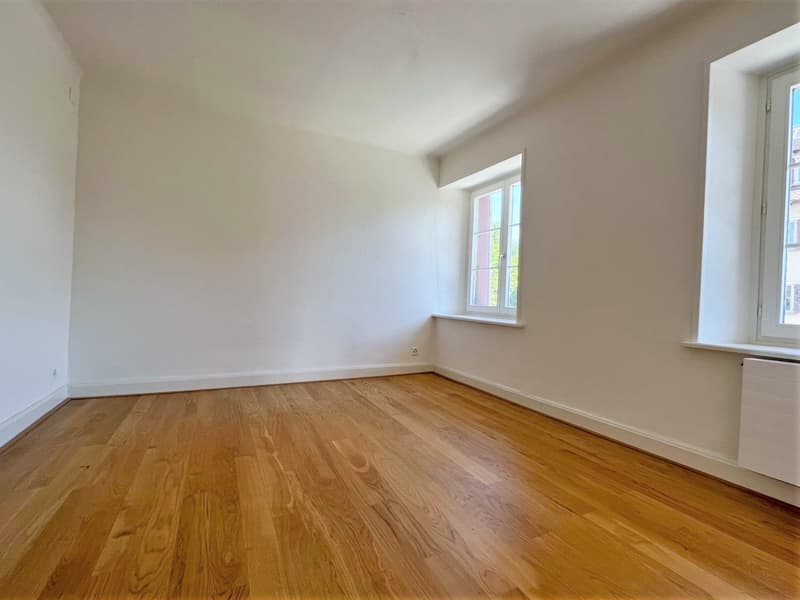 empty room with hardwood floors, white walls, and two windows with white frames