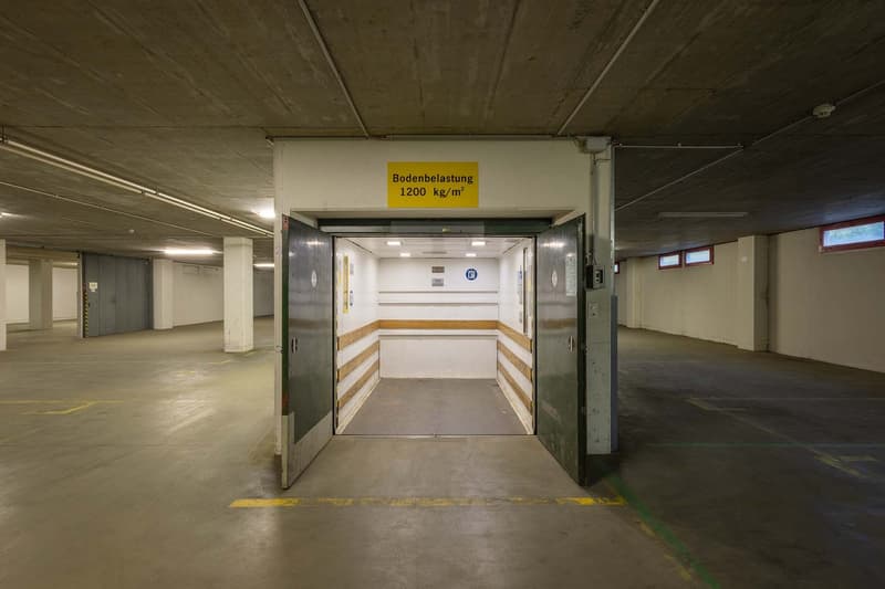 Empty parking garage with yellow markings on the floor and sign indicating the maximum weight per square meter