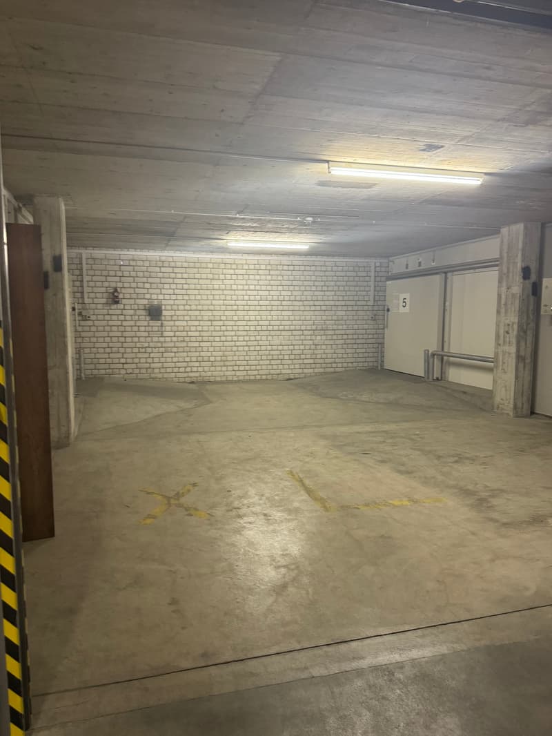 Empty parking lot with white brick wall, yellow lines, and parking bays marked