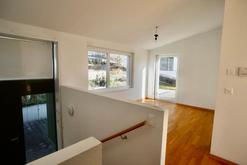 Entrance with wooden floor, white walls, and two doors, with large windows.