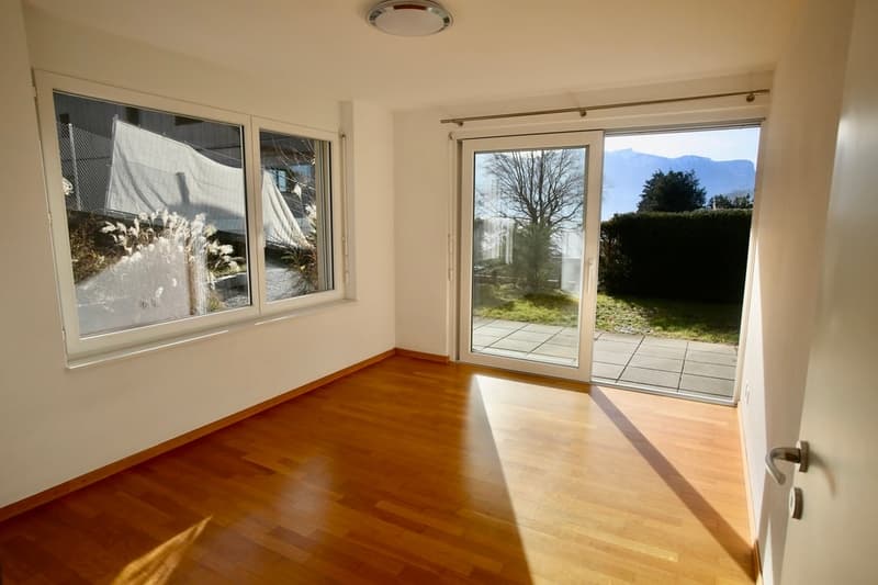 Empty room with hardwood floor, large windows, sliding door, and ceiling lamp