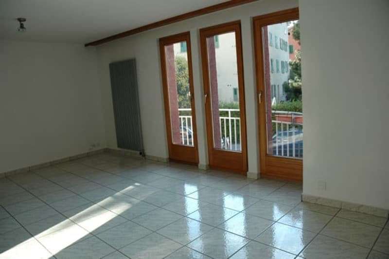 tiled floor, three large glass doors, balcony, radiator, white walls