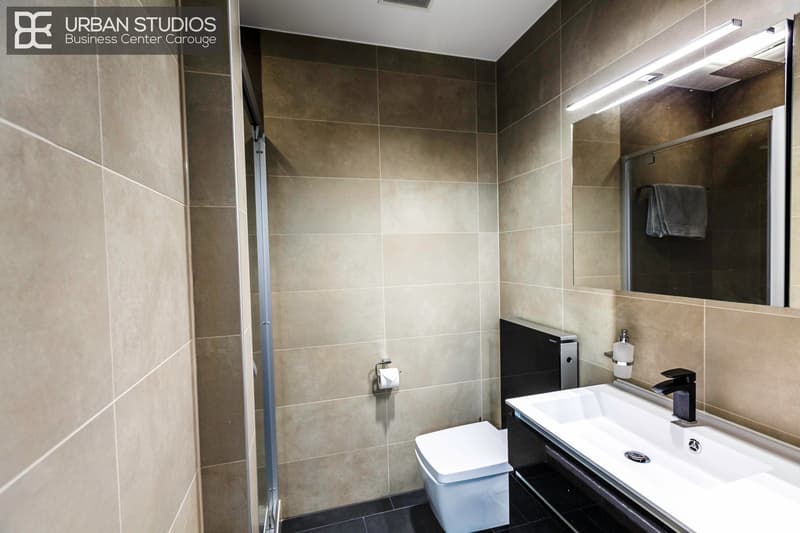 contemporary designed with light tiles, white fixtures, shower enclosure, toilet, sink, towel rack, wall-mounted light above mirror