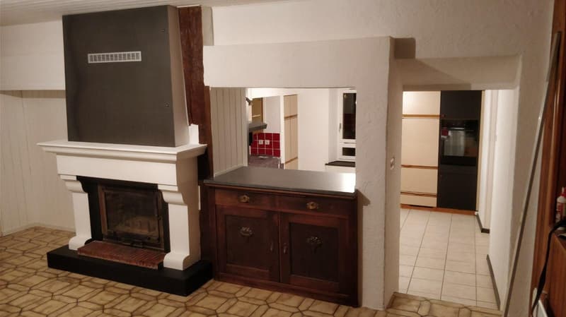 Fireplace in the corner, cabinet, open kitchen with tile flooring