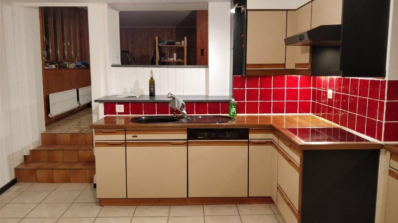 kitchen with wooden countertop, tile flooring, stainless steel sink and faucet, dishwasher, wine bottle, red tiles on the wall, gas stove