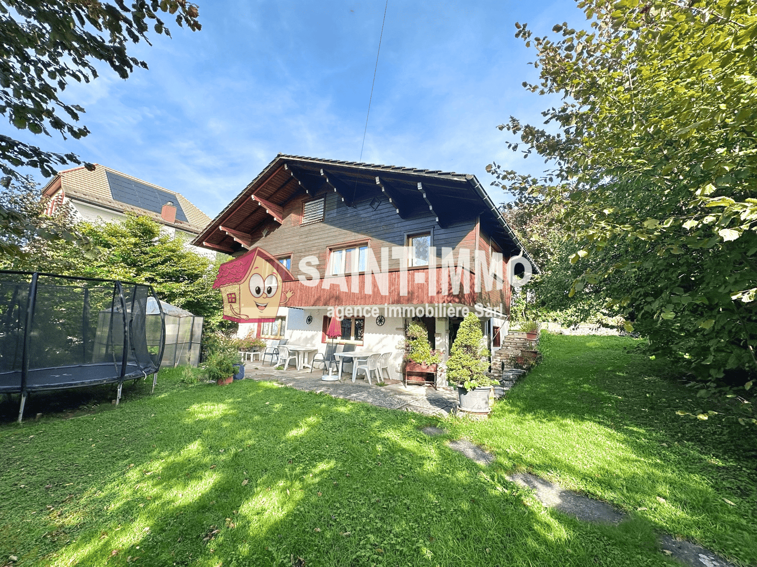 Wooden chalet house, wooden balcony, solar panels, grass yard, trampoline, potted plants