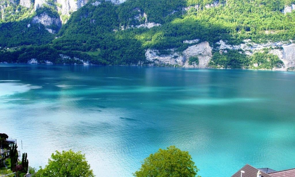 Scenic view of a turquoise lake surrounded by lush green mountains and forests