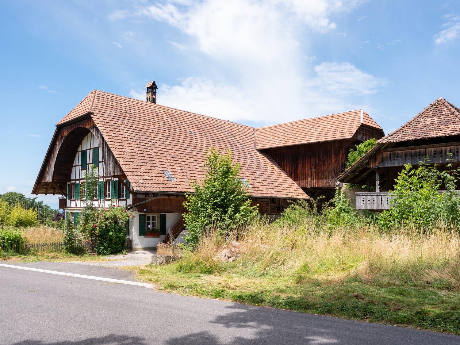 Traditional wooden house, brown roof, green windows, white walls, chimney, balcony