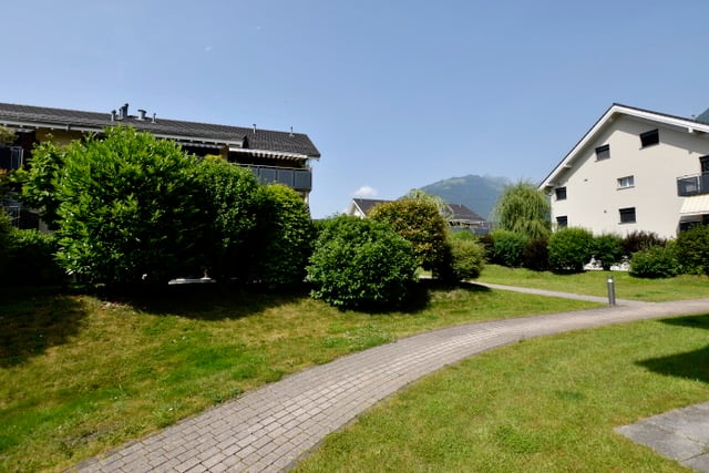 brick pathway, well-kept grass, shrubs, houses, balcony