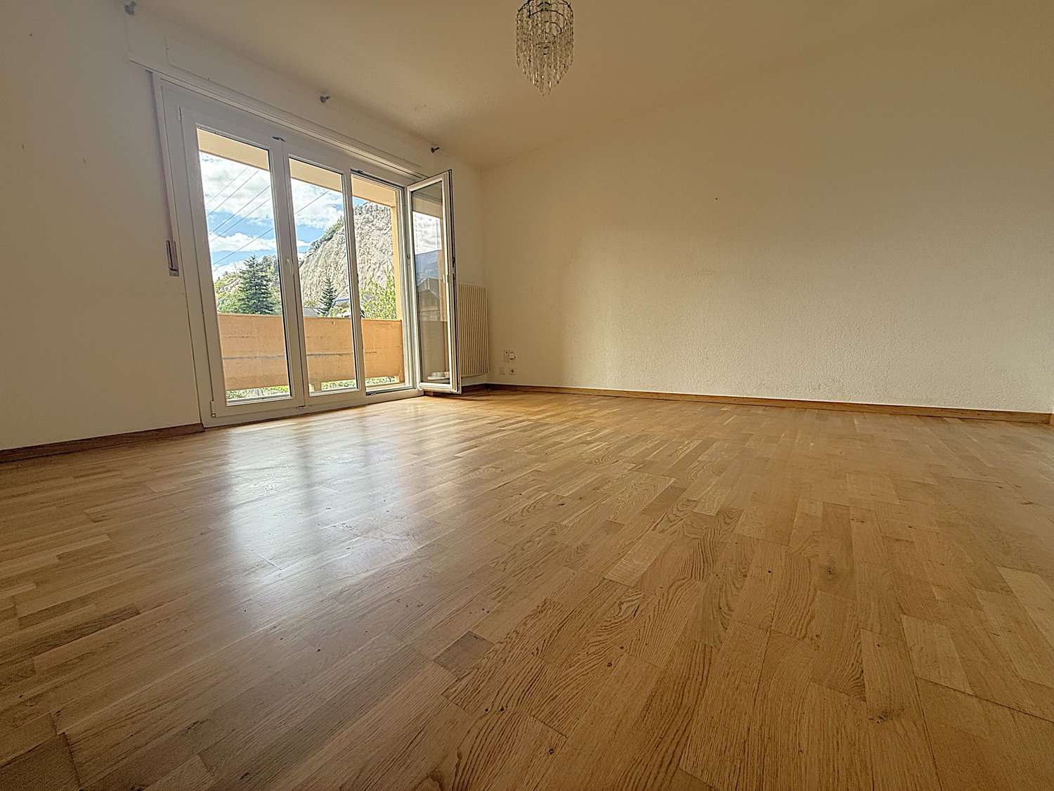 empty room with hardwood floors, white walls, sliding doors leading to balcony