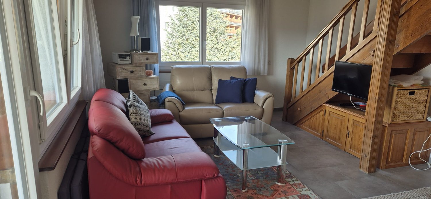 large couch, coffee table, TV, small table with speaker, window, stairs