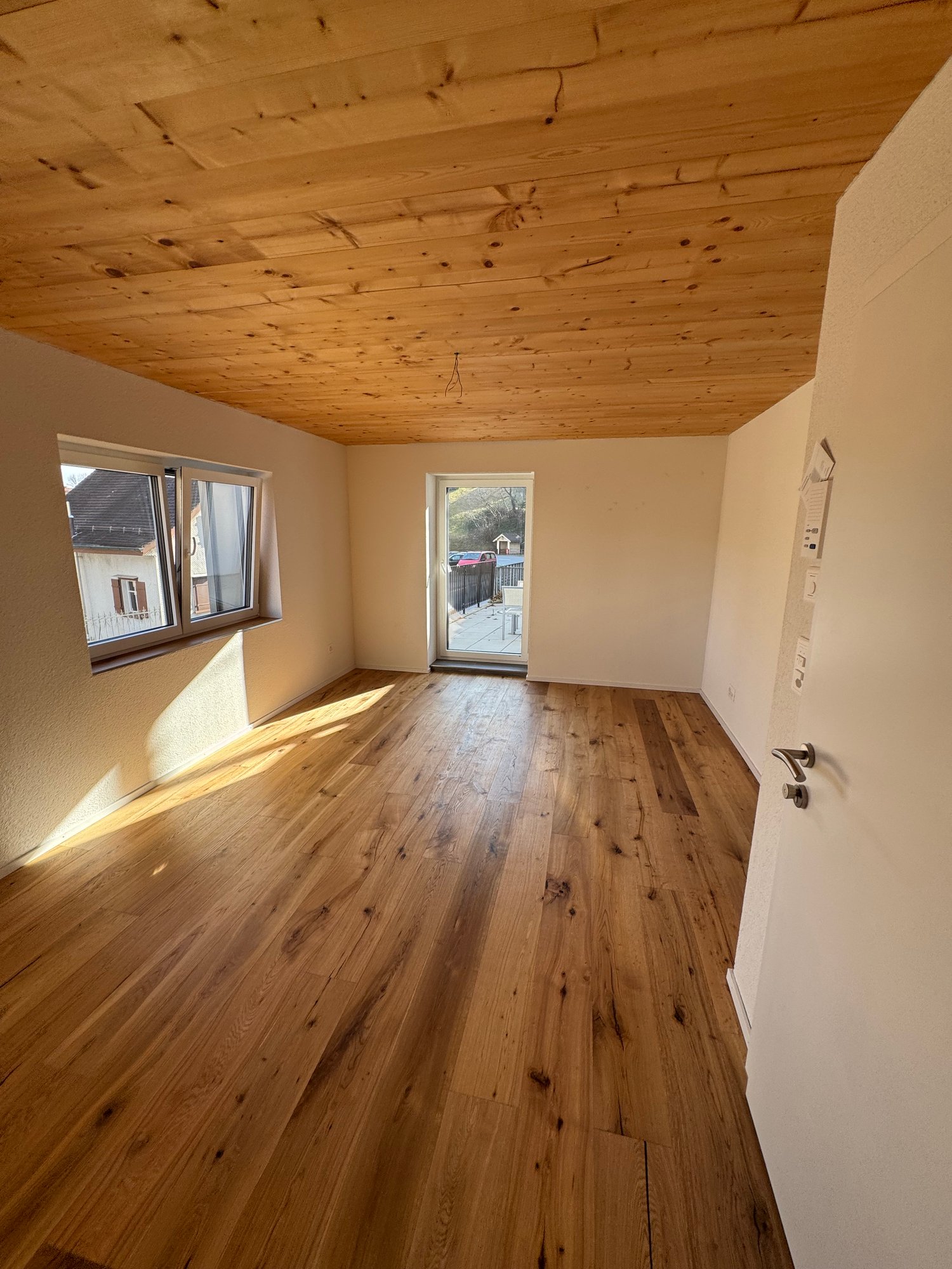 empty room with wooden floor, ceiling, glass door and window