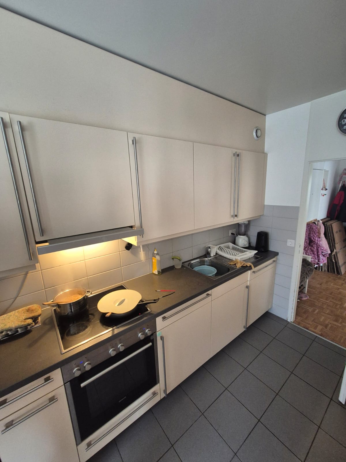 modern kitchen with appliances like washing machine and gas stove, sink, cabinets, tiles on the floor