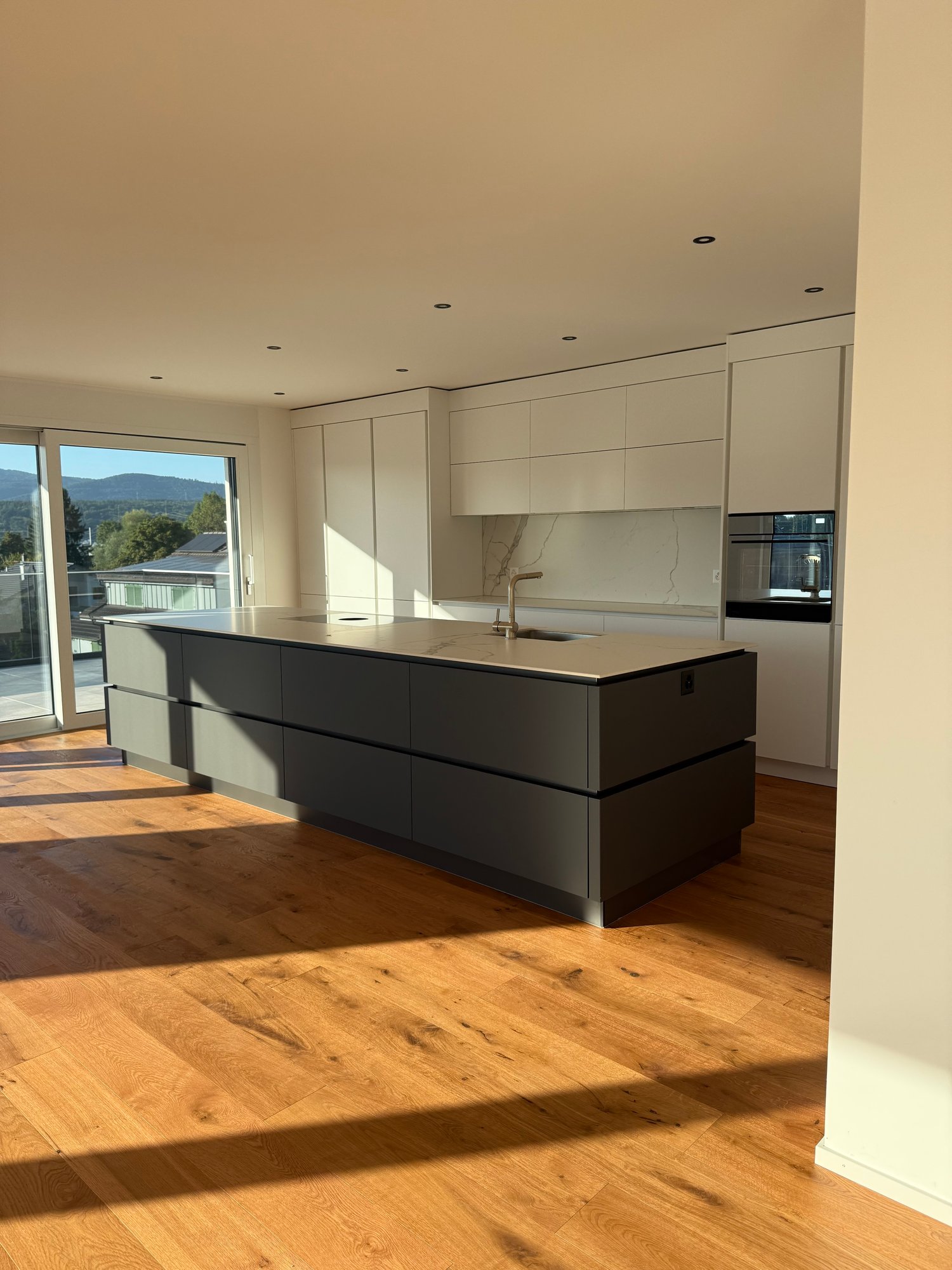 Open kitchen with island, white cabinets, granite countertops, marble backsplash, stainless steel faucet, wooden floors, sliding glass door