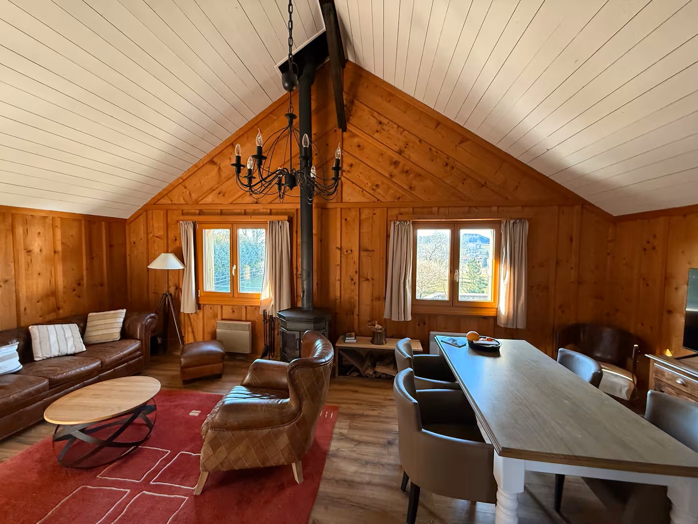 fireplace, wooden walls, chandelier, dining table, chairs, couch, rug, coffee table