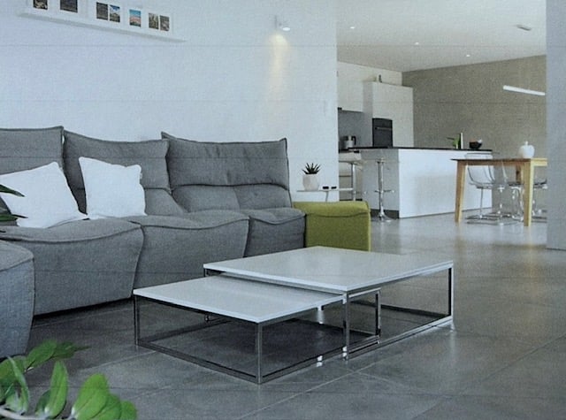 modern living room, gray sectional couch, white coffee tables, green ottoman, large windows, kitchen area