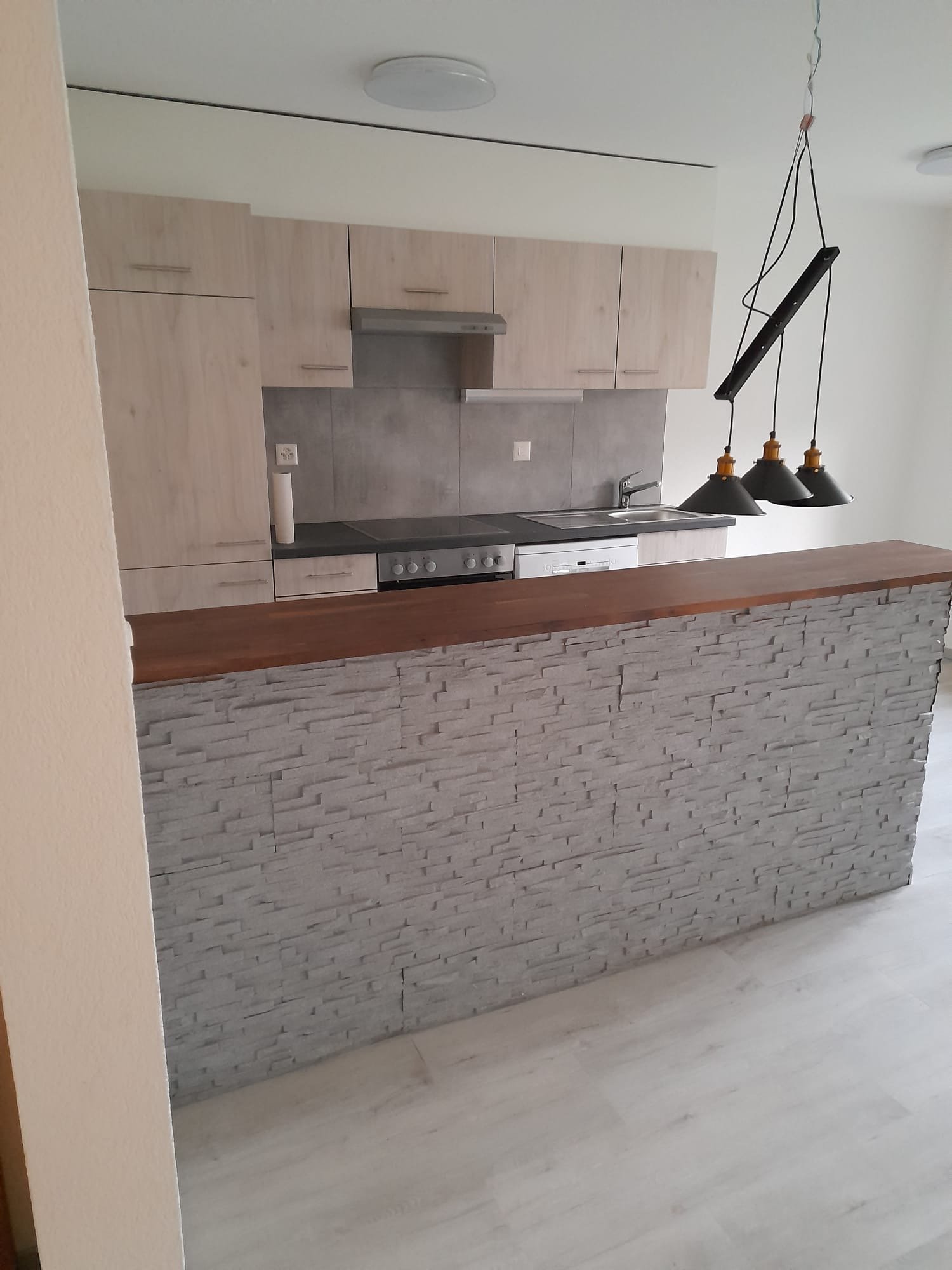 modern kitchen, gray wall, wooden countertop, white cabinets, dishwasher, built-in oven, hanging lights, wooden flooring