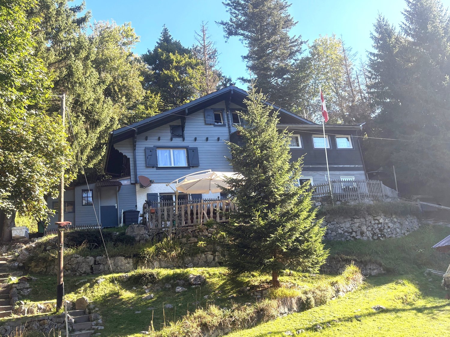2 story house, slate roof, white windows, trees, flag, fenced yard, patio, satellite dish