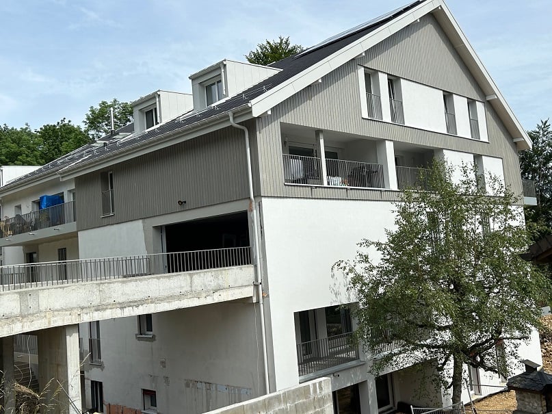 3-storey house, balconies, gray walls, solar panels on the roof, tree in front