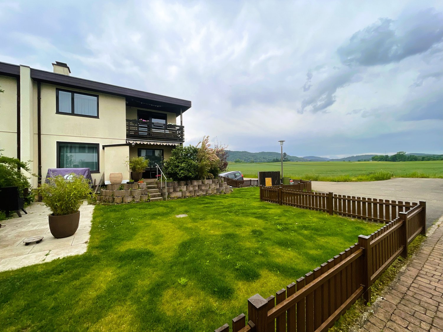 Detached house with balcony, garden, gravel driveway, large open field in the background