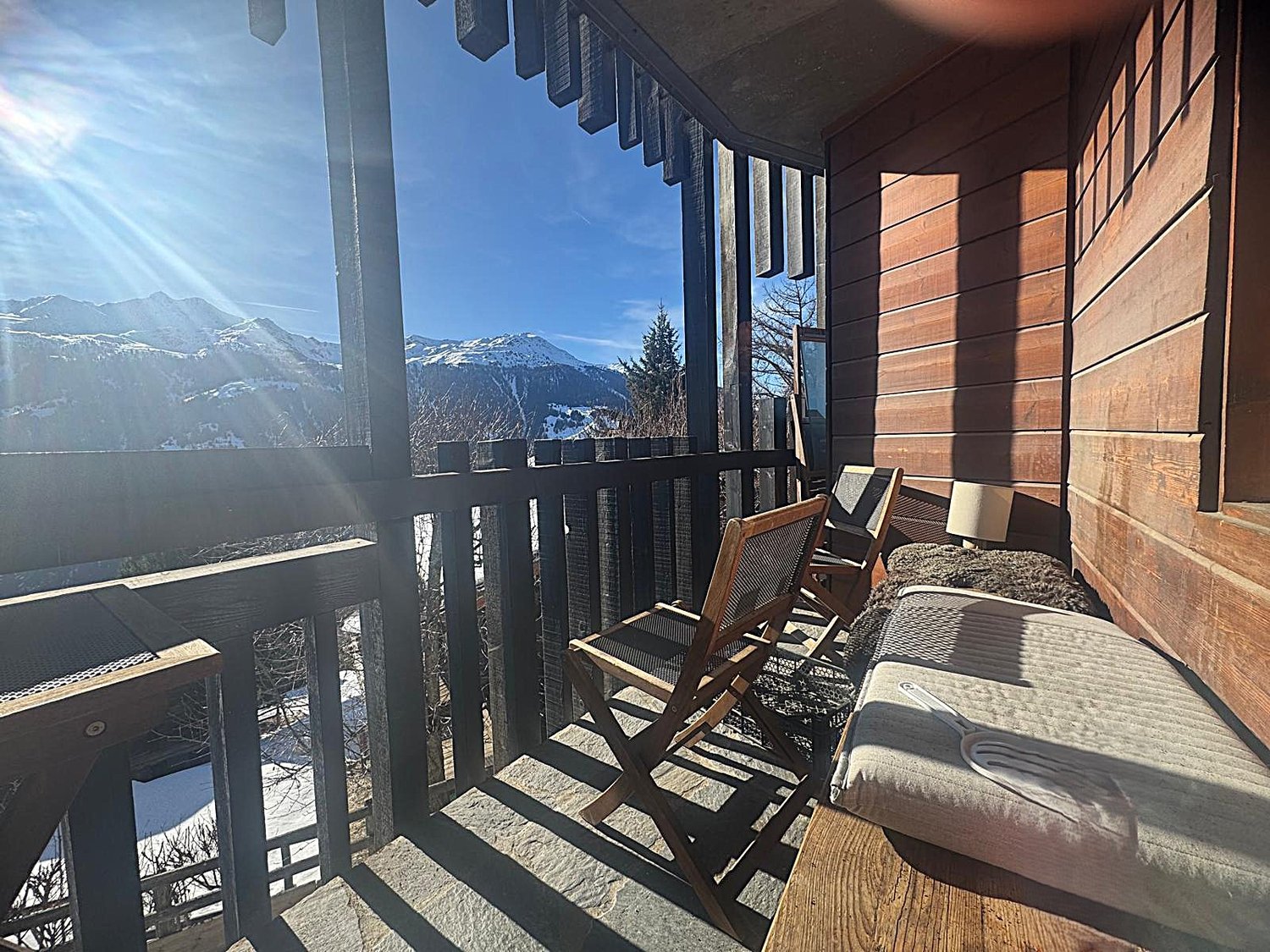 wooden balcony with railings, wooden chairs, lamp, wooden bench, view of mountains