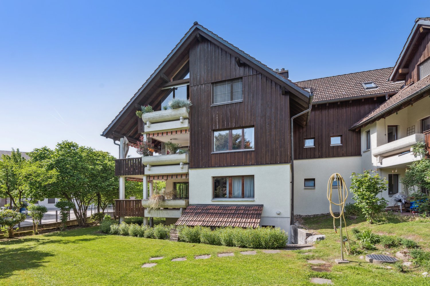 House with wood and brick walls, several balconies, large garden, plants
