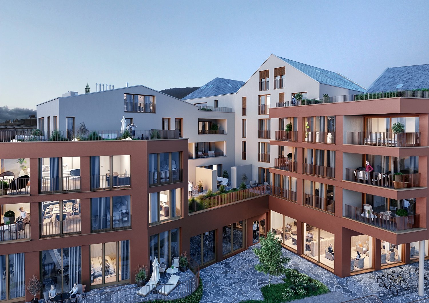 Multi-story apartment building with modern, colorful facade design. The building has balconies and terraces, and there appears to be a paved courtyard or parking area in the foreground.