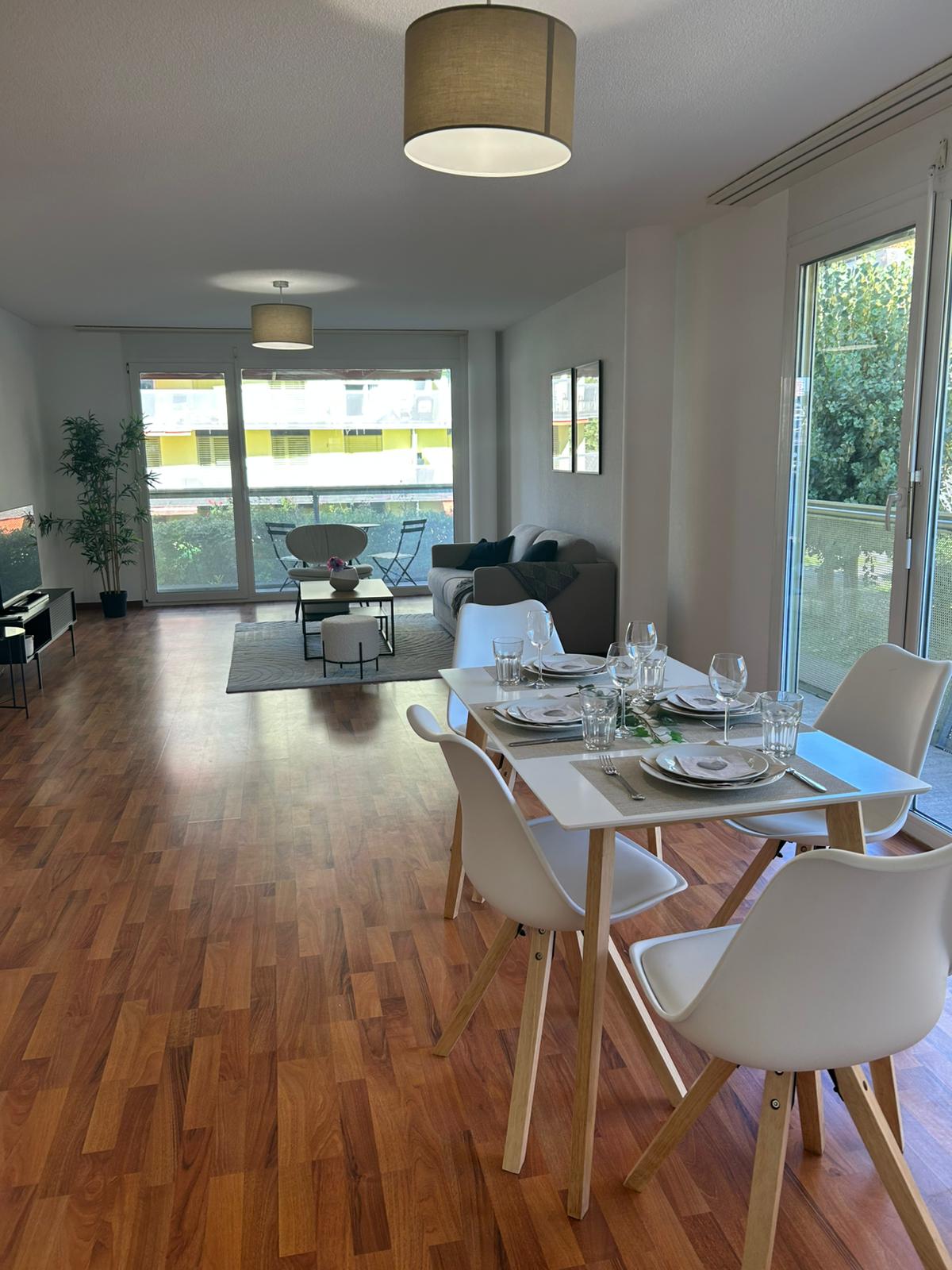 dining table with 6 chairs, modern lamps, wooden floor, large windows, balcony, couch, coffee table, TV