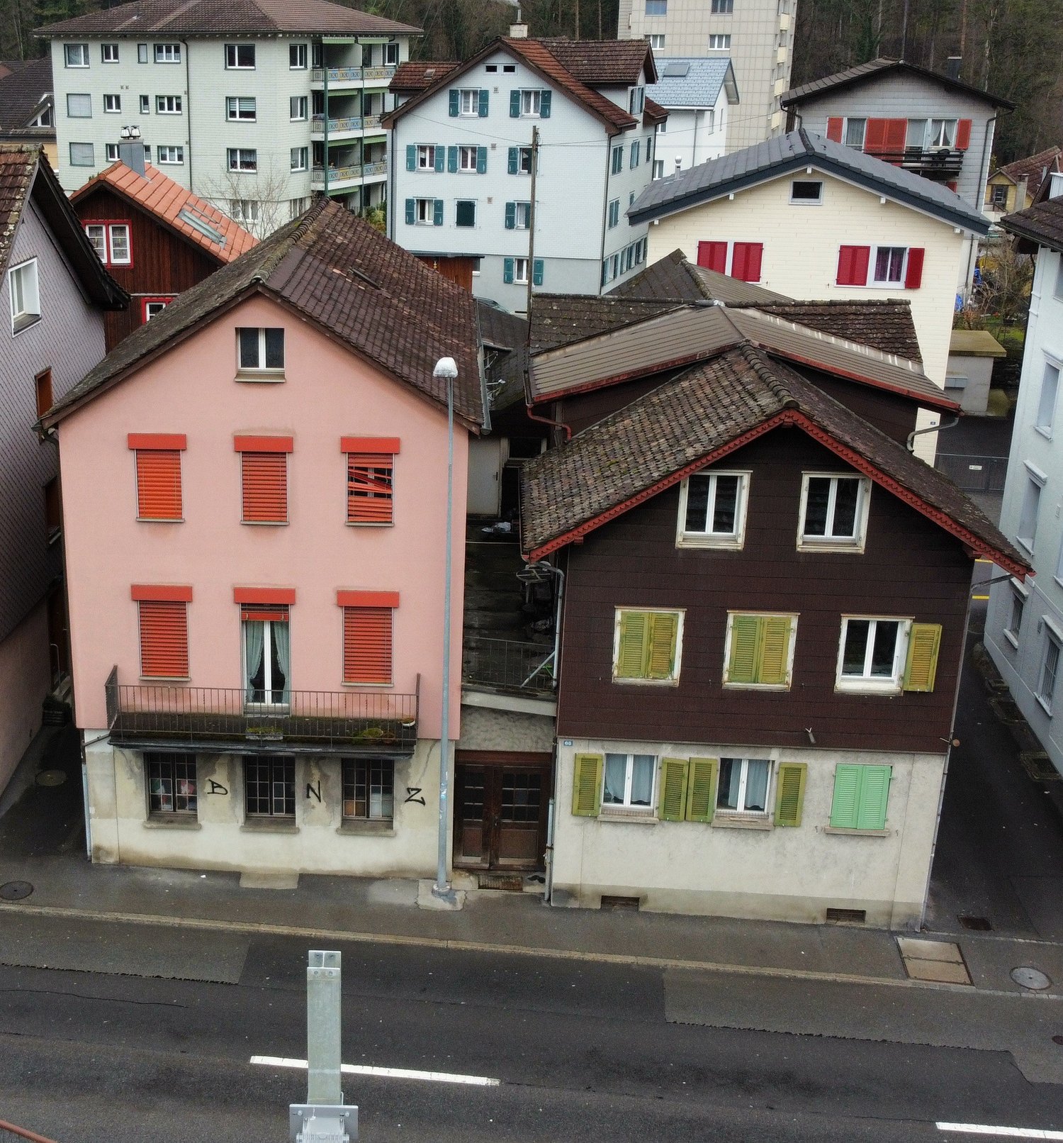 multistory building, brown roof, pink building, windows with shutters, metal railing on balcony
