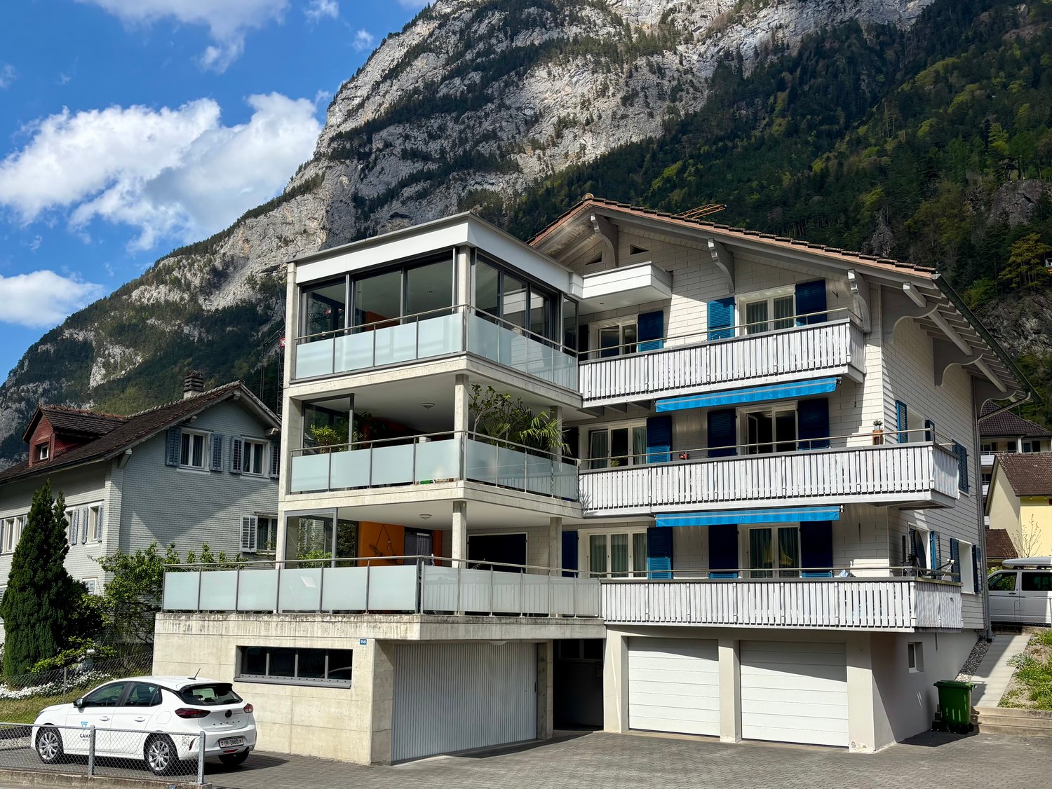 3 story apartment building, white exterior, blue shutters, balconies, garage, mountain view