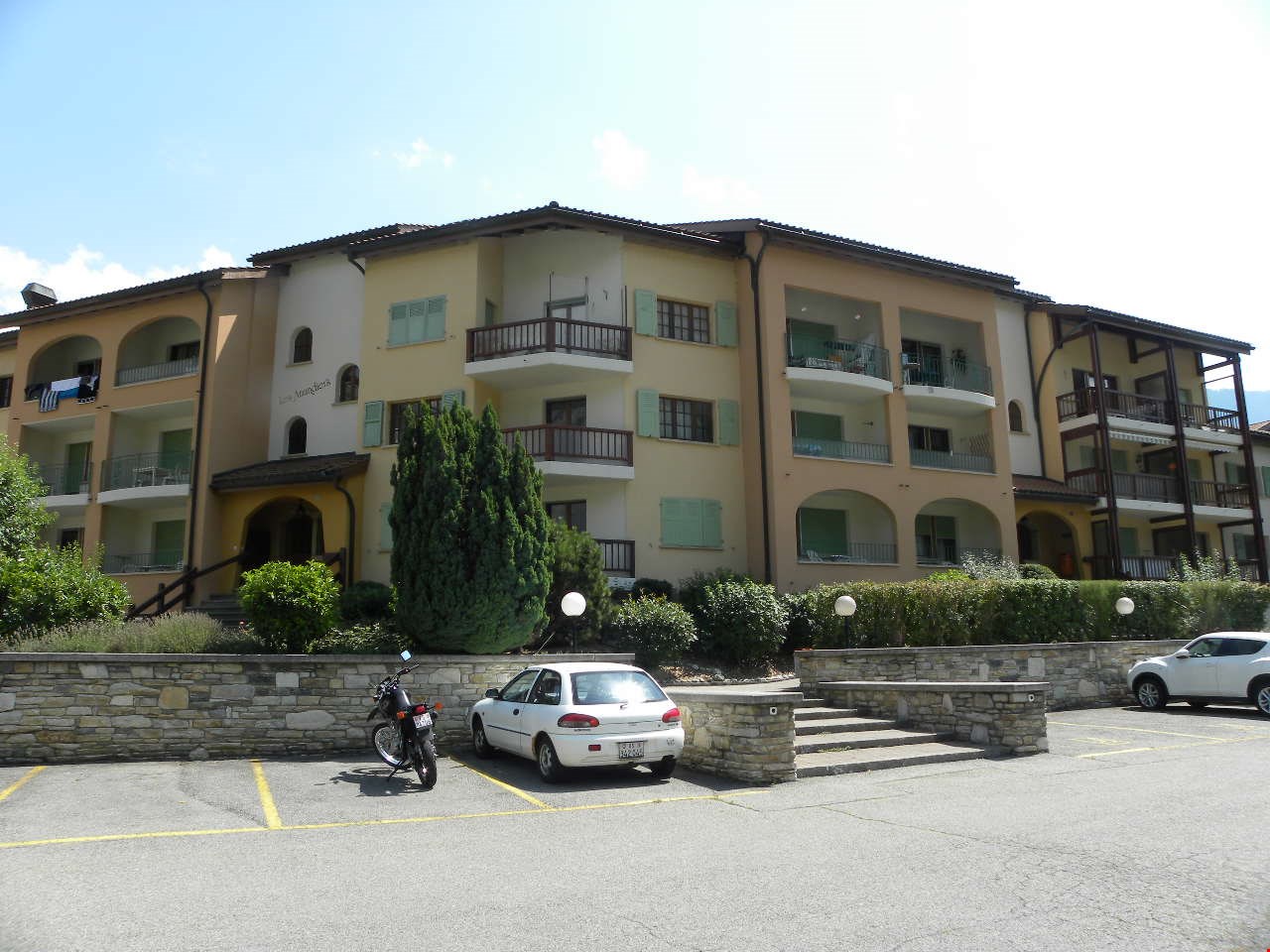 Apartment building, 4 stories, balconies, parked motorcycle and car