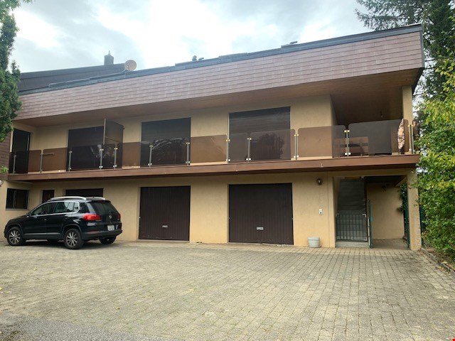 2-story apartment building with beige exterior, multiple balconies, and garages on the ground floor.