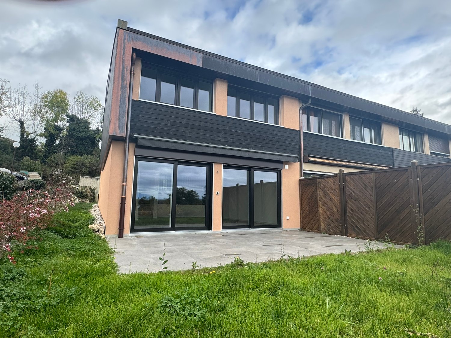 2-story house, modern architecture, glass doors, patio area, black railings, paved walkway, fenced garden