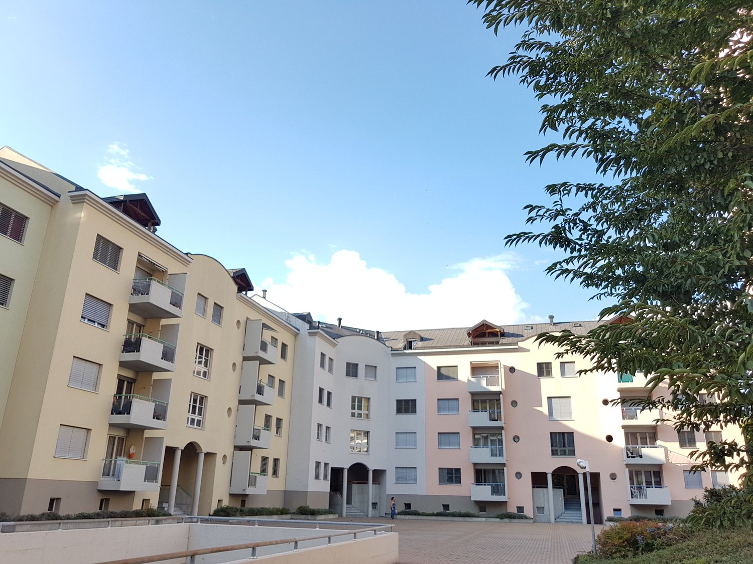 5-story building, yellow and white exterior, balconies, paved courtyard