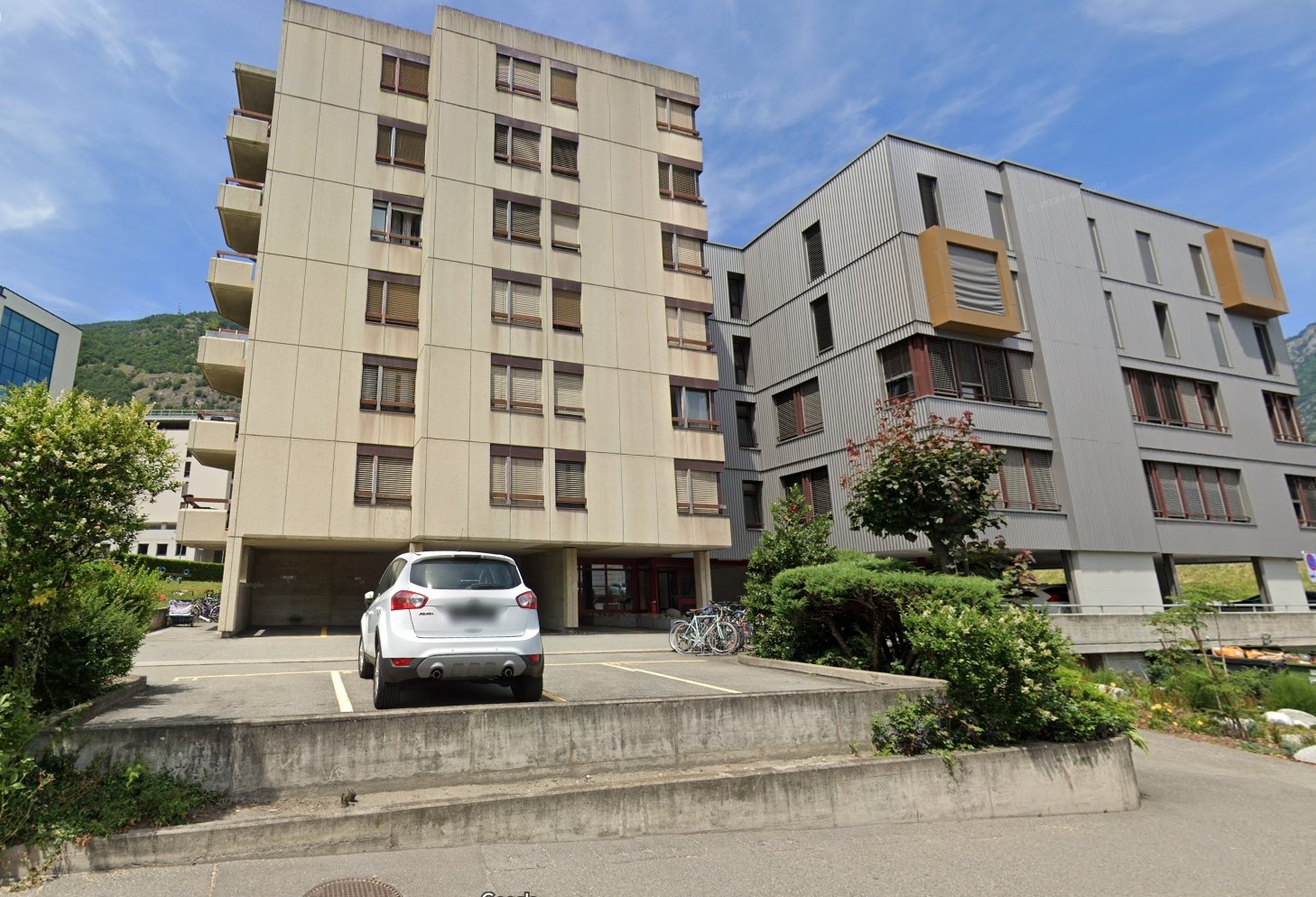 Multi-story residential building with parking lot and bicycles parked in front