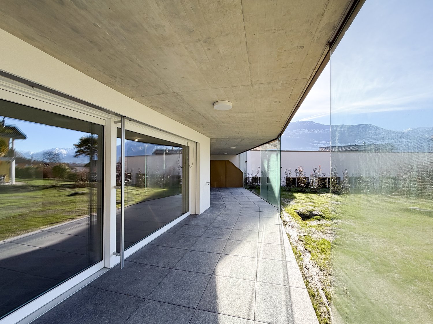 Modern building with glass walls, tiled floor, outdoor terrace, and view of mountains